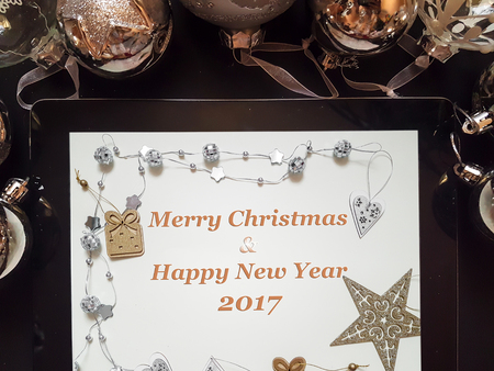 Christmas and New Year background with decorations and silver balls on dark board with tablet with Merry Christmas and happy new year text, top view, flat layの写真素材