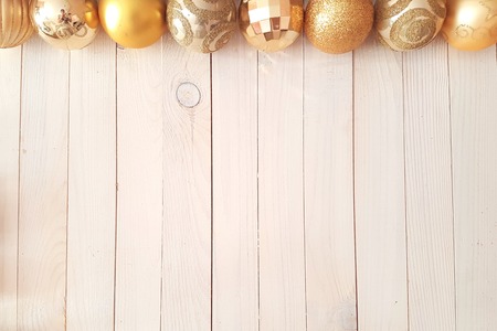 Top view of Christmas holiday background with white vintage wooden deck table over festive christmas gold balls. New Year concept, flat layの写真素材
