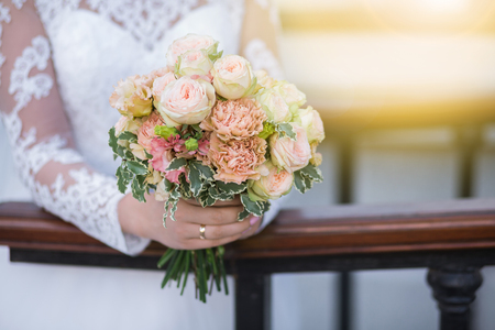 Wedding. Beautiful Weding bouquet of different flowers in the hands of the bride in a white wedding dress. Bride with a wedding bouquet on sunny day. Wedding sunshine conceptの写真素材