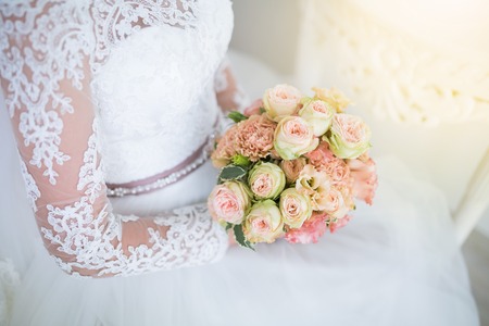 Wedding. Beautiful Weding bouquet of different flowers in the hands of the bride in a white wedding dress. Bride with a wedding bouquet on sunny day. Wedding sunshine conceptの写真素材
