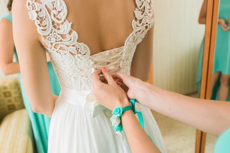 Wedding. Bridesmaid dresses bride for the wedding day. Bridesmaid helps bride with a wedding dress before the ceremony. Luxury bridal dress close up. Best wedding morning. Wedding conceptの写真素材