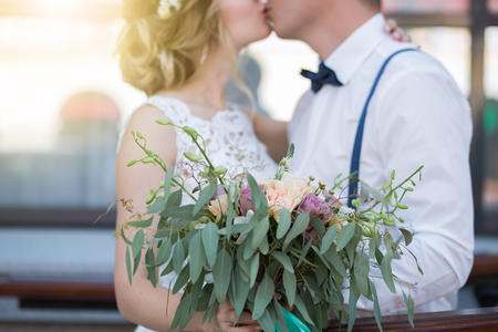 Wedding. Beautiful Weding bouquet of different flowers in the hands of the bride in a white wedding dress. Bride with a wedding bouquet holding grooms hand. Wedding ceremonyの写真素材