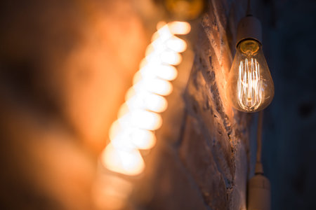 Light bulb lamp on dark red brick background with hotspot close up. Loft Horizontal texture. Grange...