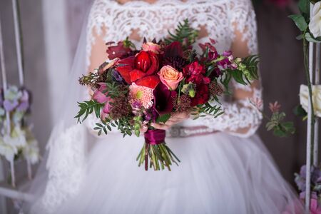 Beautiful Weding bouquet of different flowers in the hands of the bride in a white wedding dress. Bride holding grooms hand. Wedding ceremony conceptの写真素材