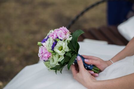 Beautiful Weding bouquet of different flowers in the hands of the bride in a white wedding dress. Bride holding grooms hand. Wedding ceremony conceptの写真素材