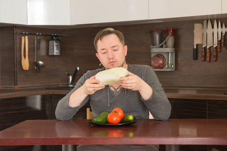 Diet. Dieting concept. Healthy Food. Young man in the kitchen chooses vegetables. Weight Lossの写真素材