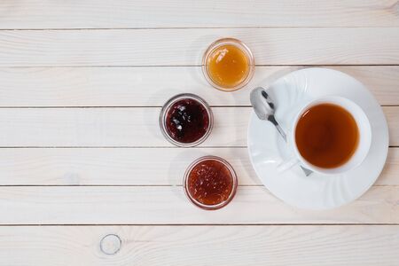 Breakfast with cup of tea and jam on rustic wooden white background, top viewの写真素材