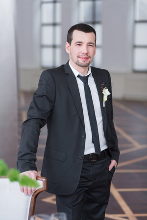 Handsome elegant groom in black wedding tuxedo with white shirt smiling and waiting for the bride. Rich groom on the wedding day.の写真素材