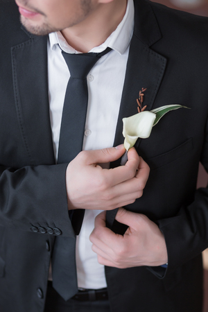 Grooms buttonhole from a white callas with green sheets. Beautiful boutonnier in groom suitの写真素材