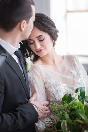 Groom and bride with wedding bouquet hold each other by handsの写真素材