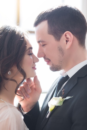 Sensual portrait of a young couple in Wedding day indoors near a big windowの写真素材