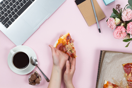 Top view of office gadgets, coffee, mobile phone and pizza on a pink background, flat layの写真素材