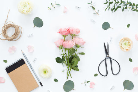 Festive composotion with flowers, notebook, gifts, scissors, ribbons, leaves on a white background, top view and flat lay, floral frameの写真素材