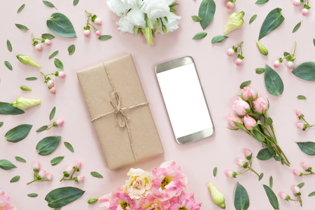 Flower arrangement on a white background with a mobile phone in a floral frame, top view and flat layの写真素材