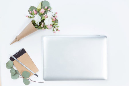 Top view of home office desktop of laptop, flowers on cone and notebook. Flat lay of workspace with copy spaceの写真素材