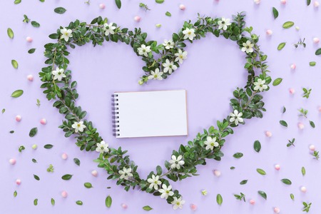 Top view of heart symbol made of natural flowers, buds, leaves and notebook. Love concept, flat lay.の写真素材
