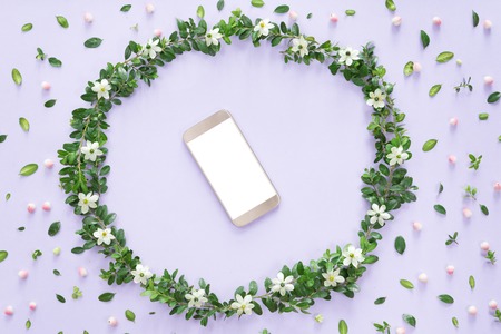 Flower arrangement or composition with a mobile phone in a floral frame, view from above, flat layの写真素材
