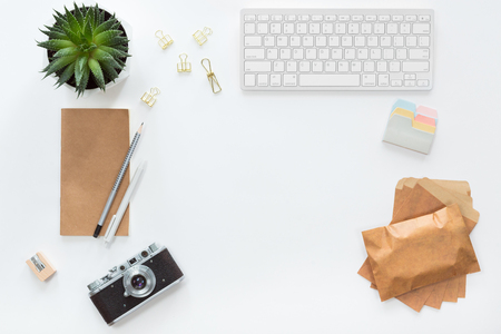 White workplace with flat lay with camera, green cactus, keyboard, smartphone, pen, notebook on office background for copy space, top viewの写真素材