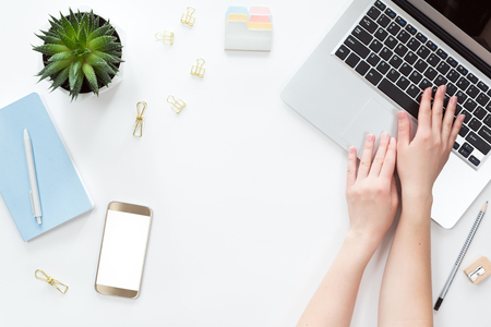 Top view of woman hand holding mobile phone with white copy space screen, flat lay on workspace tableの写真素材