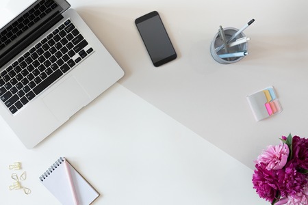 View from above of woman business workplace with computer keyboard, notebook, pink peony flower bouquet and mobile phone, flat lay.の写真素材