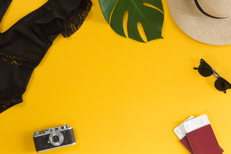 Top view of traveler accessories, swimsuit, hat, glasses, camera, passports and air tickets, tropical palm leaf on yellow summer background with copy space for text. Travel vacation concept. Flat layの写真素材