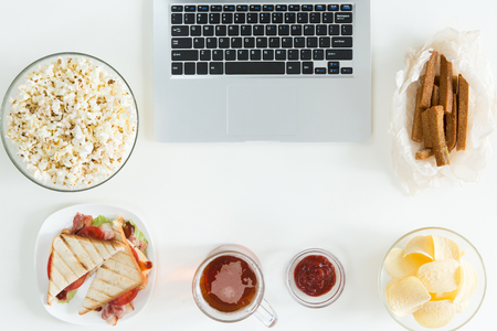 Top view of Snacks and unhealthy food with laptop on white desk, gamer conceptの写真素材