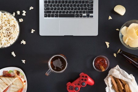 Top view of Snacks and unhealthy food with laptop on black background, gamer conceptの写真素材