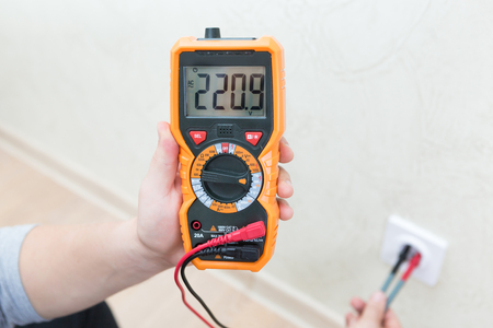 Close-up of man measuring and cheking power supply voltage with digital multimeterの写真素材