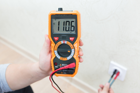 Close-up of man measuring and cheking power supply voltage with digital multimeterの写真素材