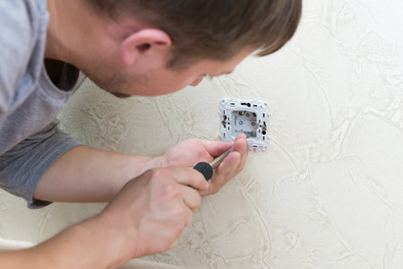 Male electrician puts on and repair an electrical outlet