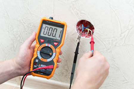 Close-up of man measuring and cheking power supply voltage with digital multimeterの写真素材