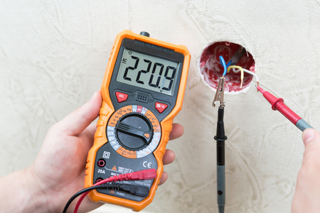 Close-up of man measuring and cheking power supply voltage with digital multimeterの写真素材