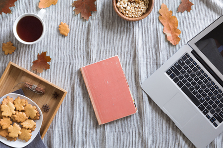 Flat lay and top view of home office desk. Workspace with woman hands, laptop, autumn leaves and flowers, cookies, coffee on cozy backgroundの写真素材