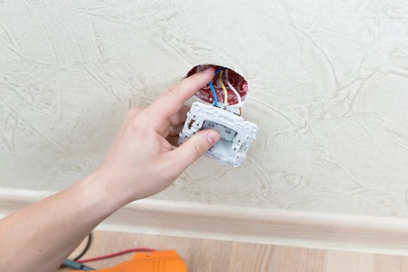 Male electrician puts on and repair an electrical outletの写真素材
