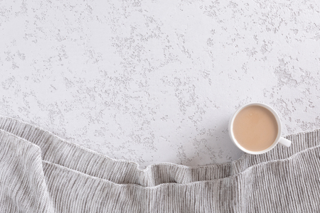 Coffee cup with milk and knitted blanket on white table. Top view, flat lay with copyspace for textの写真素材
