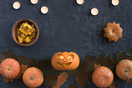 Halloween pumpkins over dark plaster background, top view, flat lay with copy space. Funny face jack-o-lantern carved in a pumpkinの写真素材