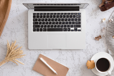 Autumn business woman morning background. Laptop, cup of coffee, notebook, camera and warm knitted blanket, flat lay, top view.の写真素材