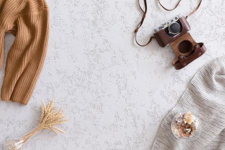 Vintage flat lay, top view. Retro camera, flowers and knitted clothes on office plaster desk table,...