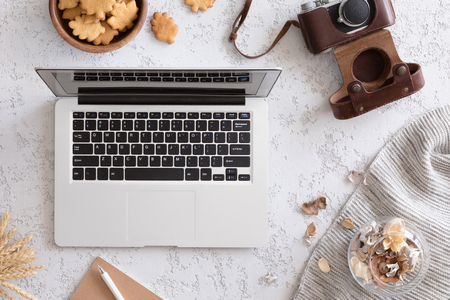 Autumn business woman morning background. Laptop, cup of coffee, notebook, camera and warm knitted blanket, flat lay, top view.の写真素材
