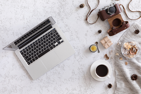 Hello Autumn flat lay background. Top view of workspace or office desk with laptop, vintage photo camera, sweater, autumn flowers and gold ears of wheat on textured white badkgroundの写真素材