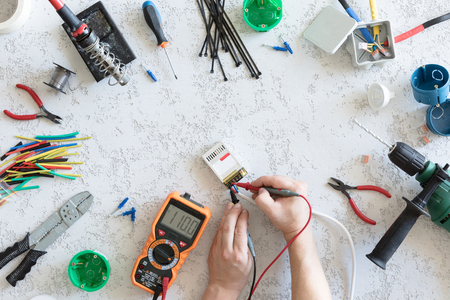 Top view of different electrical tools on white concrete background, flat lay. Tools for an electrician, measurement of voltage 110V and current measurementsの写真素材