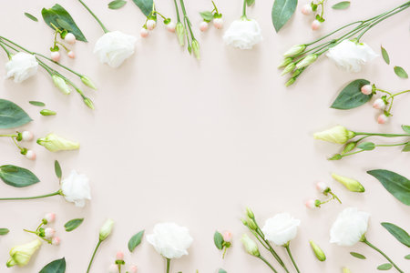 Top view of flower pattern of pink and beige buds, green leaves, branches and berries on pink...