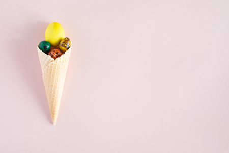 Happy Easter background with copy space. Colorful easter eggs in waffle cone on pink backgroundの写真素材