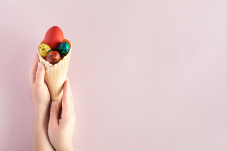 Happy Easter background with copy space. Colorful easter eggs in waffle cone on pink backgroundの写真素材
