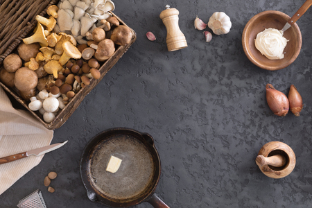 Top view of preparation and frying of edible wild mushrooms, food photo. Mix of chanterelle, portobello, shiitake in Cast-iron pan. Cooking with spices, butter, parsley, onion, leek, garlic.の写真素材