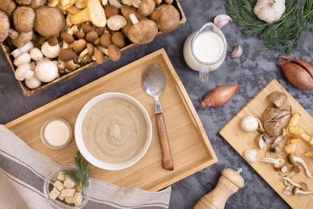 Mushroom cream soup with wild fungi, top view on dark textural background with fresh ingredientsの写真素材
