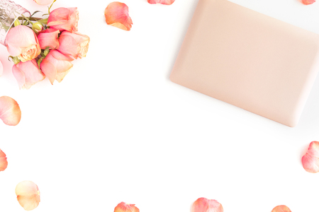 Pink gold laptop on office table desk with roses flowers and petals isolated on white backgroundの写真素材