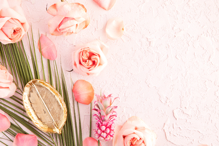 Flat lay of tropical workspace mockup with palm monstera leaves, pink flowers, pineapple and petals on pastel background. top view and copyspaceの写真素材