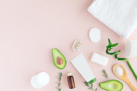 Layout of green white pink spa and wellness frame with towel, bamboo, tropical leaves , avocado, bottle of oil, body and face care tools on pastel background. Flat lay, top view.の写真素材