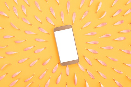 Top view of pink desk with modern gold mobile phone and flower frameの写真素材